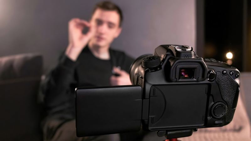 A content creator talking to a camera on a tripod while filming himself.