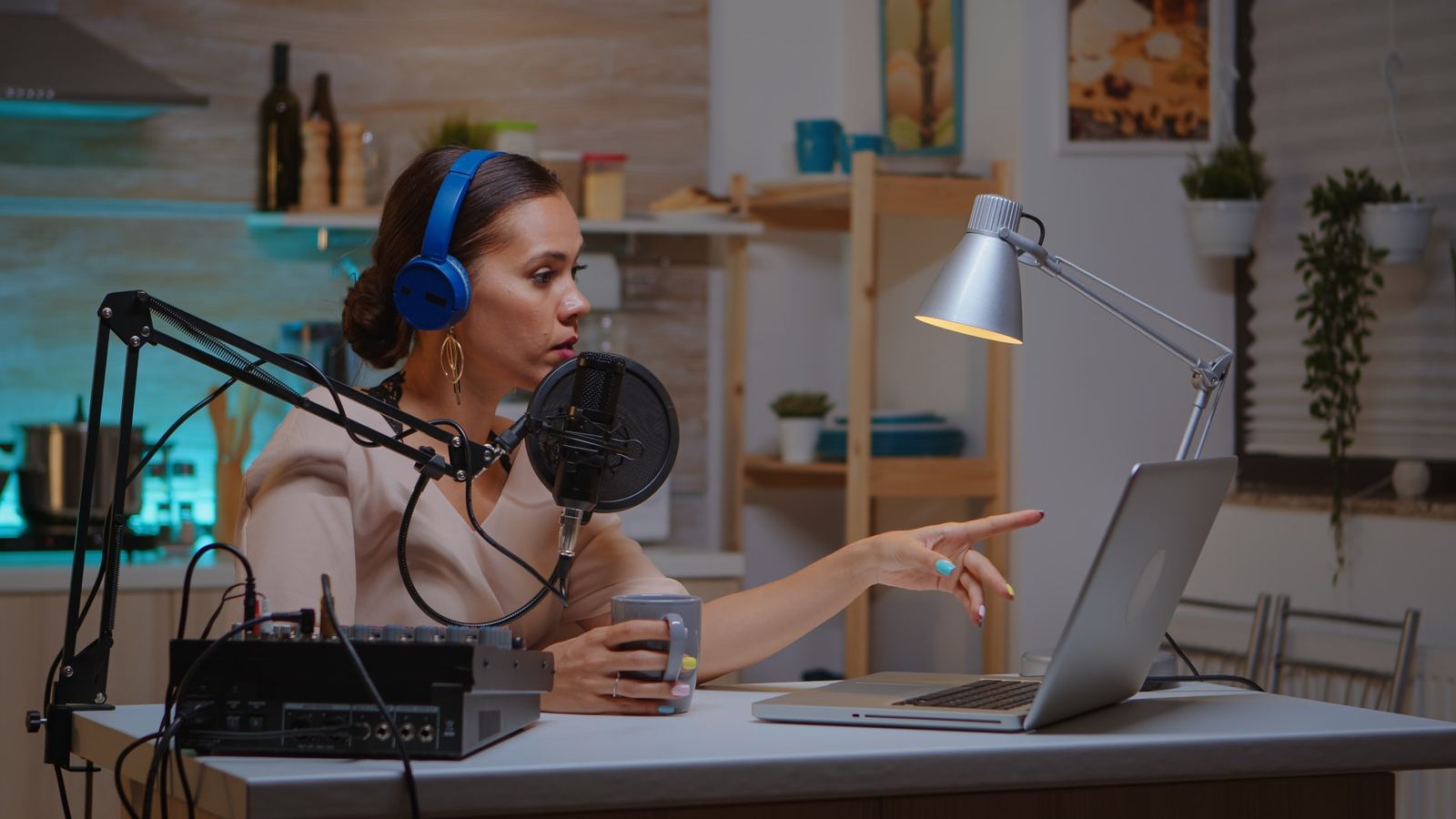 A live broadcast host speaking into a professional microphone wearing headphones in a home studio.